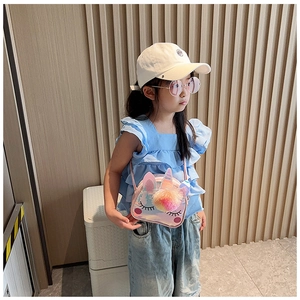 Bambina che indossa una borsa a tracolla olografica rosa a forma di unicorno con pompon