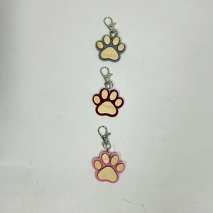 Detailed view of wood and acrylic paw-print keychains in grey, burgundy, and pink finishes