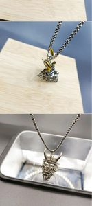 Detail of silver Oni mask pendant with gold accents on a long stainless steel chain