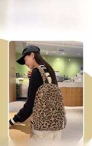 Close-up of leopard print corduroy backpack with zipper pocket and side drawstring details