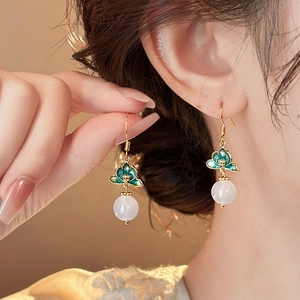 Detail of vintage flower tassel earring with green lotus motif and white pearl bead