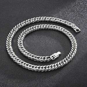 Detail of silver double-link Cuban chain with square clasp on a textured black background