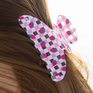 Pink and white checkerboard butterfly hair claw clip with strawberry pattern on long brown hair