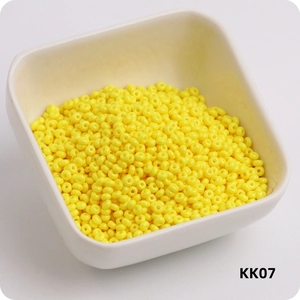 Detailed view of bright yellow 3mm glass seed beads in a white bowl, style KK07