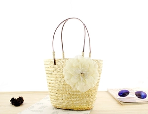 Detalle de bolso de paja artesanal con una gran flor de tul blanco y detalle de perla