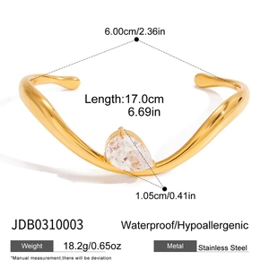 Detail view of wave-shaped gold stainless steel bangle with teardrop zircon inlay
