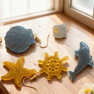 Ocean themed resin earrings featuring shell star and dolphin shapes with gold hooks