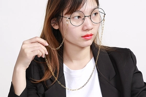 Close-up of golden rectangular link chain attached to glasses with silicone loop