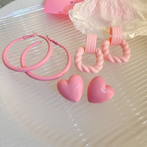 Close-up of pink acrylic heart, twist frame, and hoop earrings set on acrylic tray