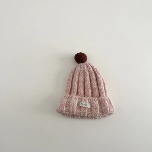 Nahaufnahme der rosa Strickmütze mit braunem Bommel und weicher strukturierter Wolle