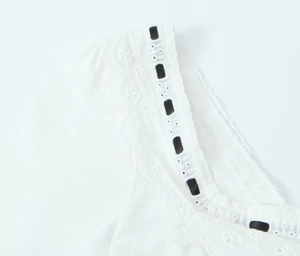 Détail de l'encolure carrée en dentelle blanche avec broderie et ruban noir décoratif