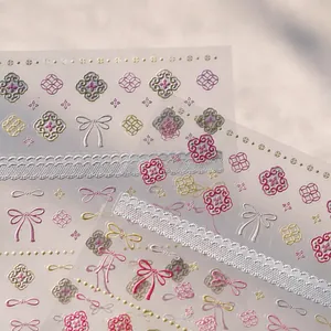 Close-up of Japanese 3D nail art stickers with elegant pink bows and golden lace