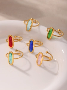 Détail de six pierres en verre colorées sur des bagues dorées torsadées et ajustables