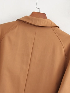 Close-up of lapel collar and raglan sleeve stitching on camel long casual jacket