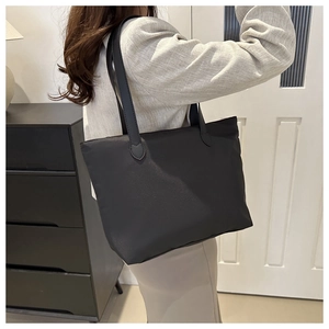 Lifestyle shot of large black nylon tote bag worn over the shoulder on female model