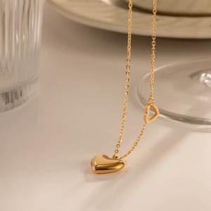 Close-up of 18K gold plated double heart pendant necklace in elegant warm lighting