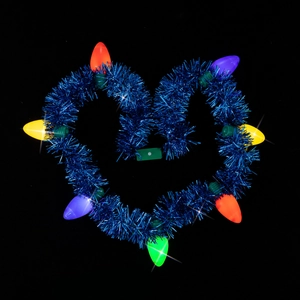 Close-up of heart-shaped blue tinsel wreath with glowing colorful LED bulbs for party