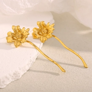 Macro shot of 18K gold plated stainless steel floral earrings on stone background