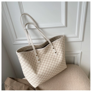 Dettaglio ravvicinato di una borsa tote monogramma panna su una sedia di peluche