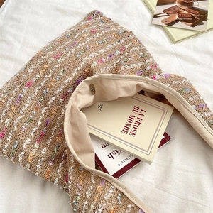 Detail of colorful knit tote bag featuring a magnetic clasp closure and interior lining