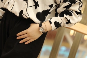 Detail of rose gold tonneau watch with rhinestone bezel and black leather strap