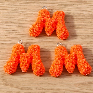 Close-up of orange letter M charms with 3D rose textures for DIY jewelry crafts