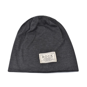 Dettaglio di un berretto slouchy in maglia grigio scuro con toppa decorativa 'ROCK'