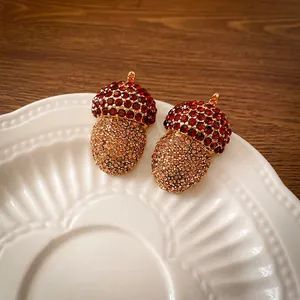 Vintage acorn pendants with red and amber crystals on a white ceramic plate