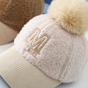 Detail of baby teddy fleece baseball cap with M BABY embroidery and faux fur pom pom
