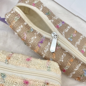 Close-up of textured tweed floral pencil cases with silver metal zippers and soft fabric lining