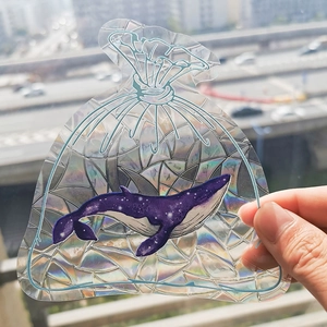 Close-up of rainbow prism window cling with laser geometric pattern and whale sticker