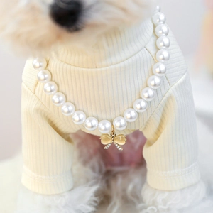 Detail of luxury dog pearl collar with gold bow pendant and opal stone on pet