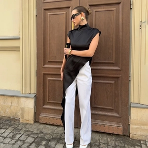 Elegant black mock neck satin sleeveless top with asymmetrical hem and white trousers