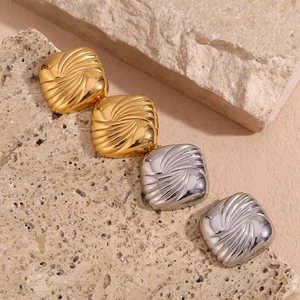 Detailed view of square metallic earrings with spiral texture in gold and silver finish