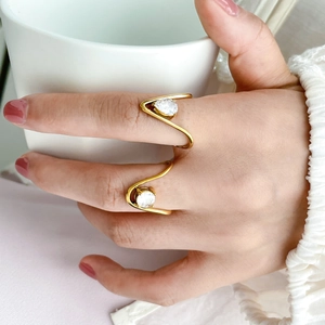 Close-up of elegant gold wave rings featuring teardrop and round zircon stones on a hand