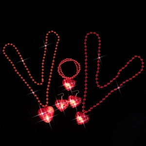 Close-up of red LED glowing heart jewelry set with necklaces spelling LOVE on black background