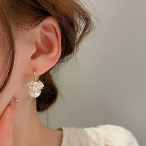 Elegant gold flower earrings with white pearls and rhinestones on female model