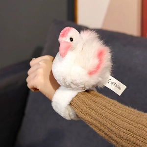 Detail of white flamingo plush snap bracelet with pink wings on a person's wrist