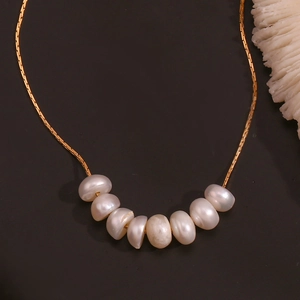 Detalle de collar de acero chapado en oro de 18K con 8 perlas de agua dulce y fondo oscuro