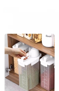 Close-up of clear grain storage jar with scale markings and white handle lid in a pantry