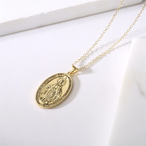 Dettaglio della collana con ciondolo Madonna dorata e zirconi lucenti su base marmo