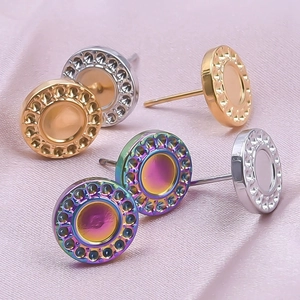 Close-up of circular stainless steel stud earrings in gold, silver, and rainbow on pink silk