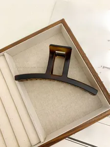 Close-up of large amber textured hair claw clip in a minimalist rectangular frame design