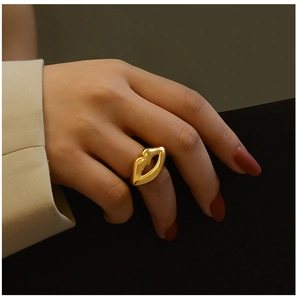 Close-up of a gold-plated lip-shaped ring on a model's hand with red-brown nail polish