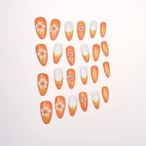 Détail de faux ongles amande avec dégradé orange et décorations florales en relief