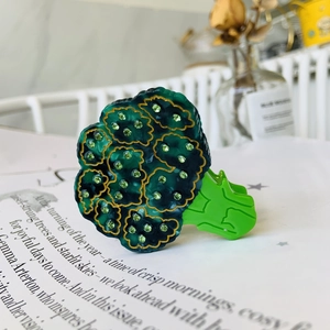 Detailed close-up of a creative broccoli hair claw clip with green rhinestones and gold edges