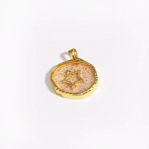 Detail of gold star and moon pendant with pink glitter resin in irregular round frame