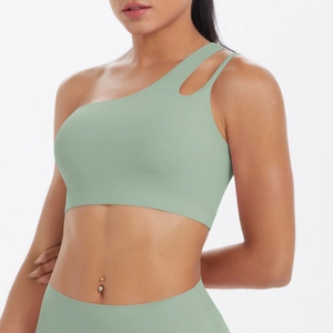Detail of sage green one-shoulder sports bra with asymmetric cutout and matte fabric