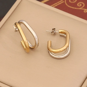 Macro shot of two-tone gold and silver C-shape geometric stud earrings on leather