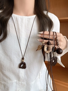 Detail view of retro wood and resin geometric pendants on an adjustable brown cord
